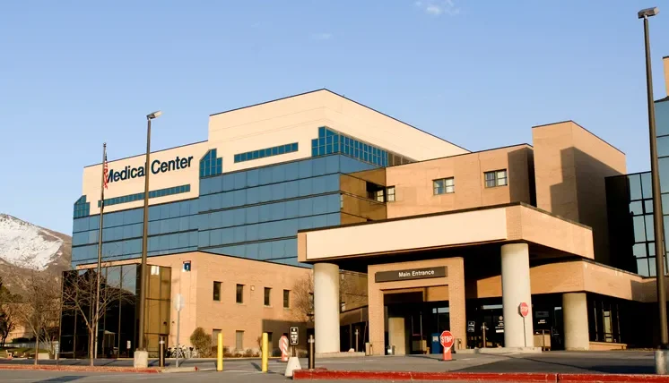 A visual representation of healthcare financial challenges, possibly showing hospital buildings with downward-trending financial graphs and policy documents.