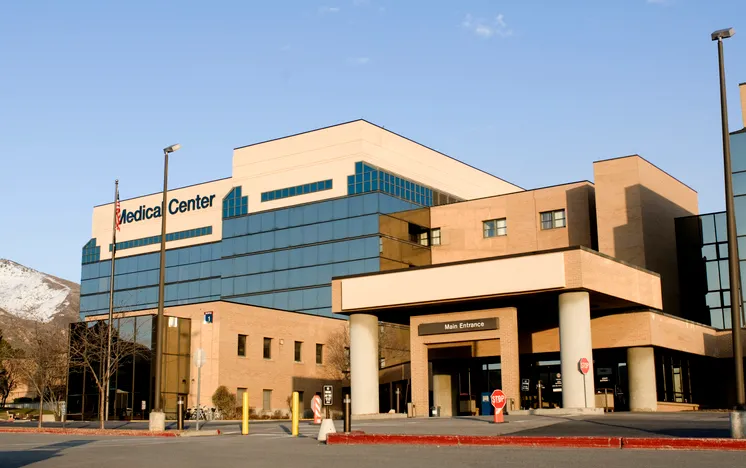 A visual representation of healthcare financial challenges, possibly showing hospital buildings with downward-trending financial graphs and policy documents.