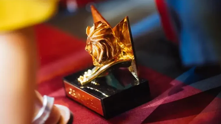 A close-up of a Cannes Lions award statue with a blurred background of a festival event