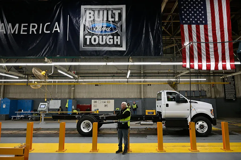 Veteran Ford engineers inspecting car parts on an assembly line, demonstrating quality control