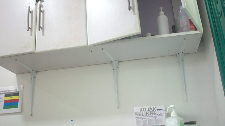 A healthcare professional interacting with an AI interface on a tablet in an Indian hospital setting, with medical equipment in the background.