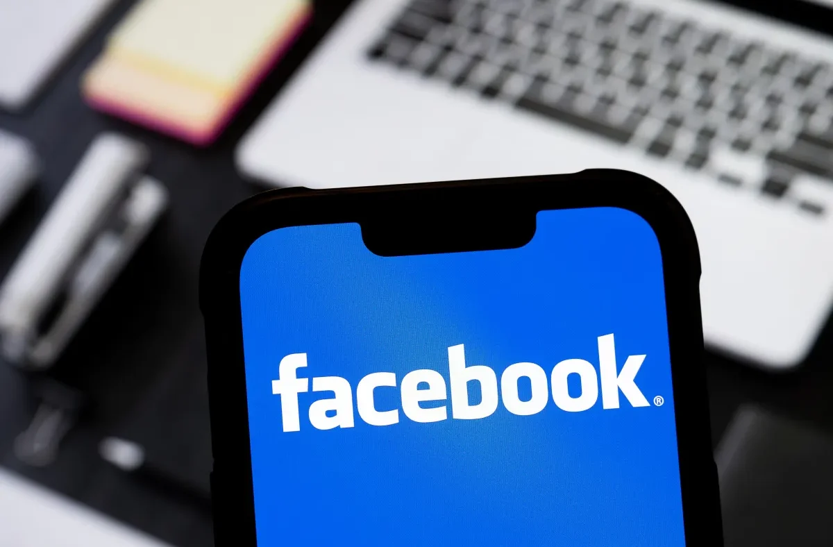 A creator looking at a smartphone displaying Facebook's new AI companion app interface, with graphs and AI-generated content suggestions