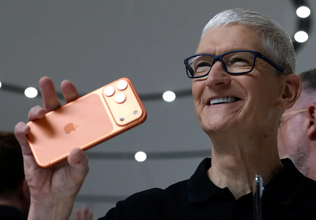 A person holding an iPhone, showcasing various practical AI features from iOS 27 like bill splitting on a receipt, smart suggestions in messages, and call context during a phone