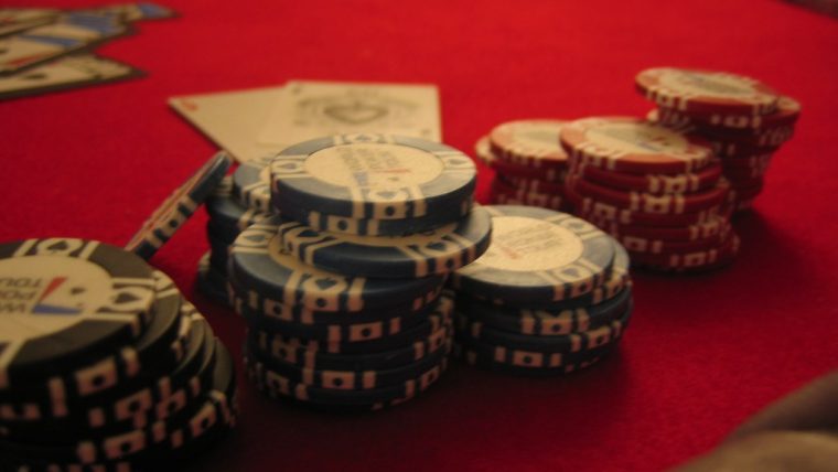 A magnifying glass over fine print terms and conditions, with blurred casino chips and cards in the background, symbolising the importance of understanding bonus rules.
