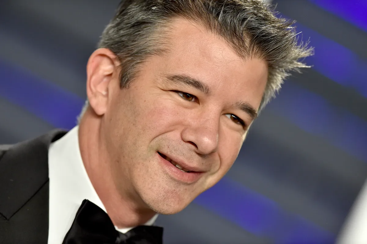 Travis Kalanick, former Uber CEO, discussing the future of industrial robotics and AI with a backdrop of automated factory machinery.